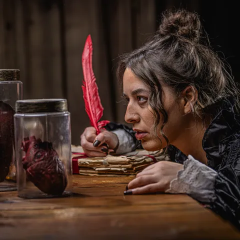 Mary Shelley Holding a quill and looking into a jar